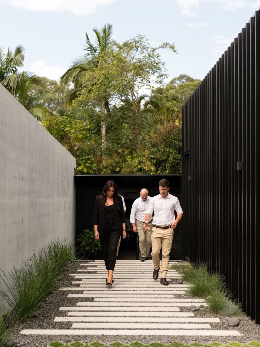 Three estate agents walking out of a contemporary house
